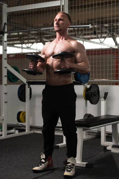 Kulturista cvičení biceps s činkami — Stock fotografie
