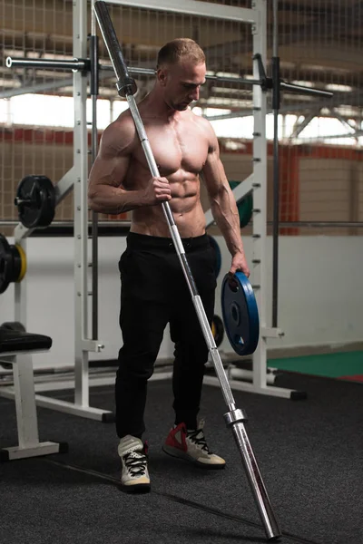 Człowiek, wyginanie mięśni ze sztangą i wagi — Zdjęcie stockowe