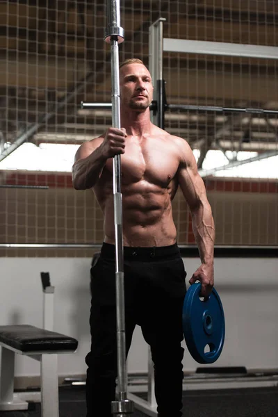 Hombre Flexing músculos con barra y pesos — Foto de Stock