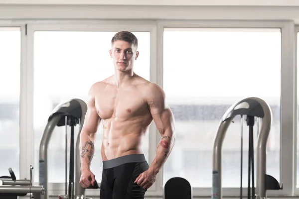 Bello muscoloso uomo flessibile muscoli in palestra — Foto Stock