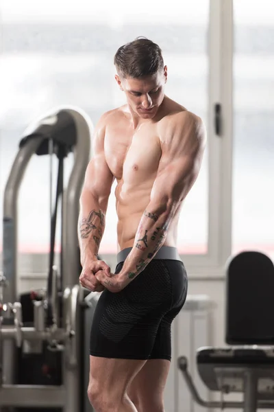 Hombre musculoso guapo flexionando músculos en el gimnasio —  Fotos de Stock