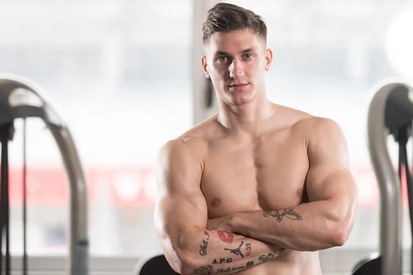 Homem muscular flexionando músculos no ginásio — Fotografia de Stock