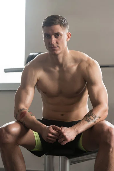 Hombre muscular descansando en el banco después del ejercicio — Foto de Stock