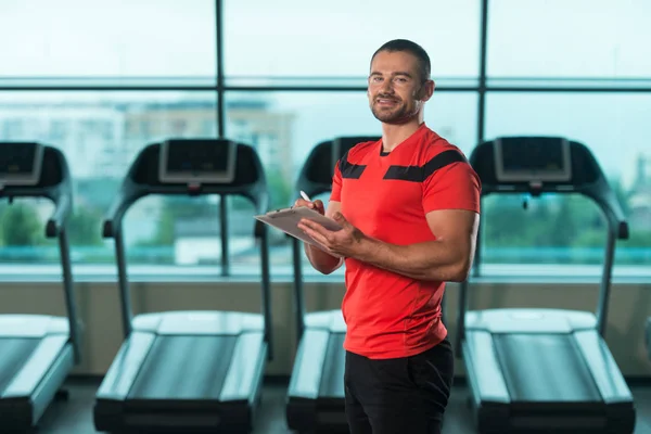 Personlig tränare tar anteckningar på Urklipp i Gym — Stockfoto
