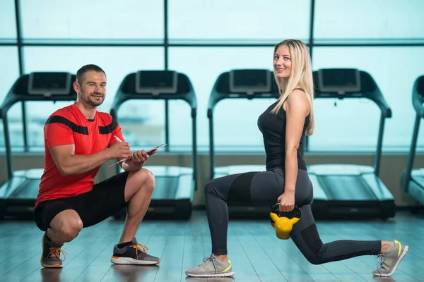 Entraîneur de gymnase aidant la femme avec cloche de bouilloire — Photo