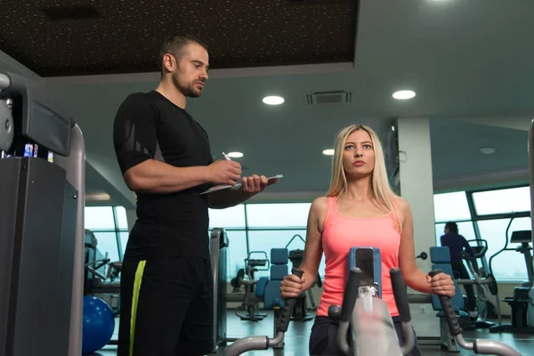 Train de femme de retour sur la machine avec entraîneur personnel — Photo