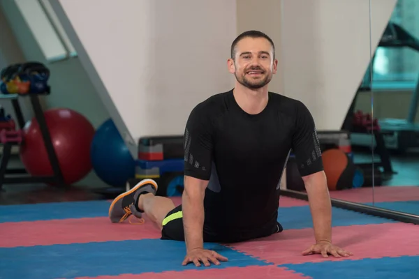 Homem de fitness jovem se alonga no chão — Fotografia de Stock