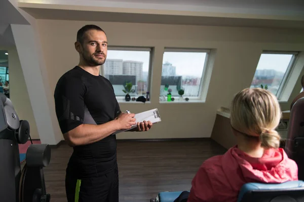 Personal Trainer Takes Notes While Woman Exercising Legs — Stock Photo, Image