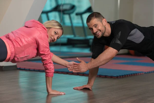 Jeune couple faisant de l'exercice push-up dans la salle de gym — Photo