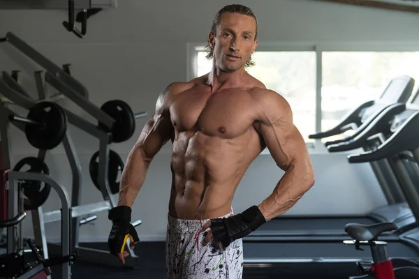 Homem muscular flexionando músculos no ginásio — Fotografia de Stock