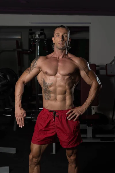 Seriöser Bodybuilder steht im Fitnessstudio — Stockfoto