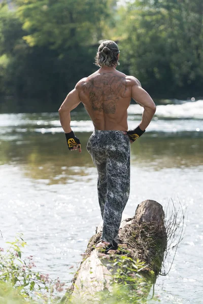 Bodybuilder buigen spieren buiten In de natuur — Stockfoto