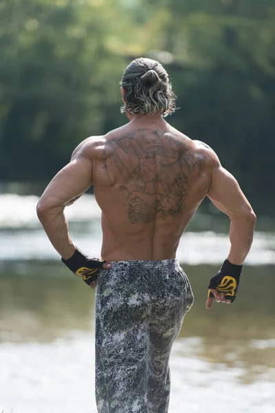 Hombre guapo Flexing músculos al aire libre en la naturaleza — Foto de Stock