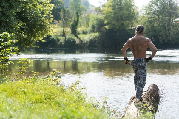 Schöner schleimiger Mann, der draußen in der Natur Muskeln spielen lässt — Stockfoto