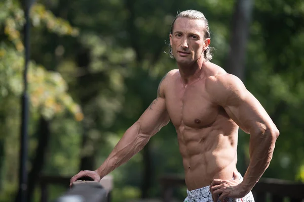 Hombre guapo Flexing músculos al aire libre en la naturaleza — Foto de Stock