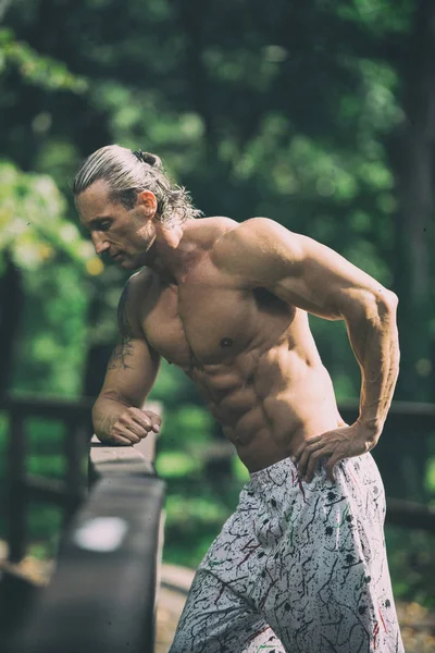 Schöner Mann, der draußen in der Natur Muskeln spielen lässt — Stockfoto