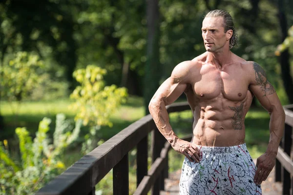 Bodybuilder flexar muskler utomhus i naturen — Stockfoto