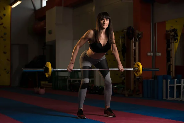 Женщина делает упражнения для спины с штангой — стоковое фото