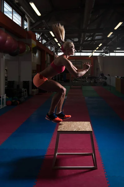 Jeune femme en forme faisant des sauts de boîte dans la salle de gym — Photo