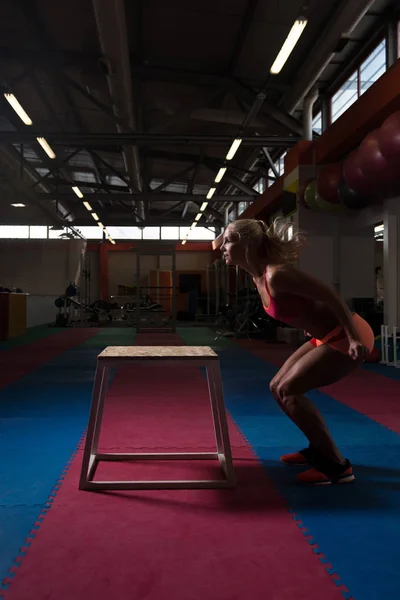 Jeune femme en forme faisant des sauts de boîte dans la salle de gym — Photo