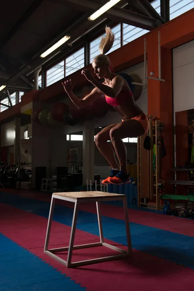 Jeune femme en forme faisant des sauts de boîte dans la salle de gym — Photo