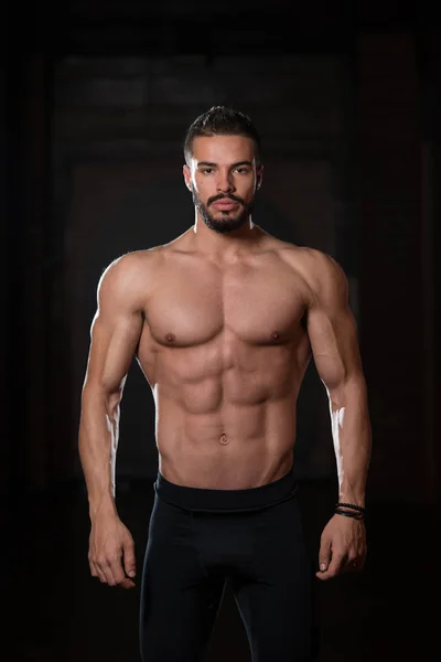 Modelo muscular guapo flexionando los músculos en el gimnasio — Foto de Stock