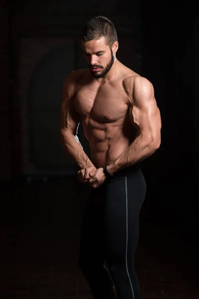 Pohledný svalnatý Model protahuje svaly v tělocvičně — Stock fotografie