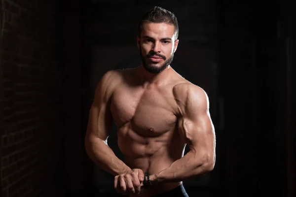 Modelo muscular guapo flexionando los músculos en el gimnasio — Foto de Stock