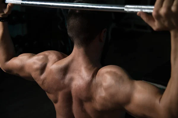 Mann im Fitnessstudio trainiert Schulter mit Langhantel — Stockfoto
