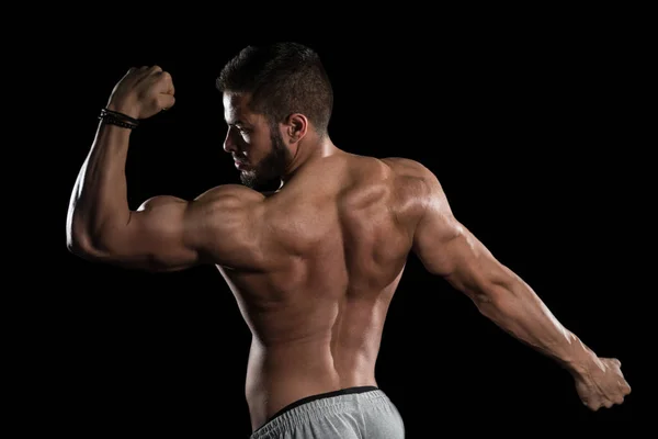 Músculos Flexing homem muscular em fundo preto — Fotografia de Stock