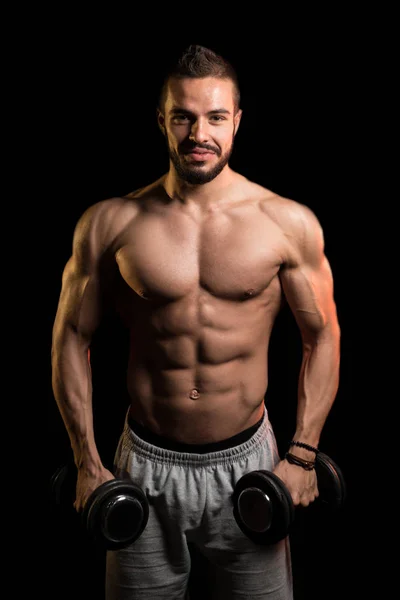 Man oefening Biceps met halters op zwarte achtergrond — Stockfoto