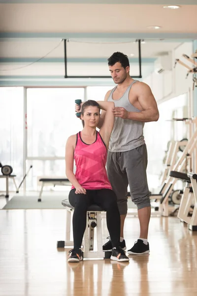 Entrenador de gimnasio ayudando a la mujer en el ejercicio Triceps — Foto de Stock