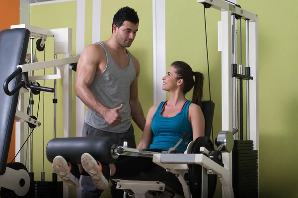 Jambes de train de femme sur la machine avec entraîneur personnel — Photo