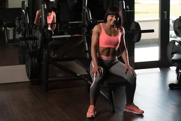 Frau ruht sich in Fitnessstudio auf Bank aus — Stockfoto