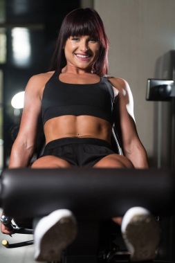 Genç kadının makine üzerinde bacaklar için egzersiz yapması