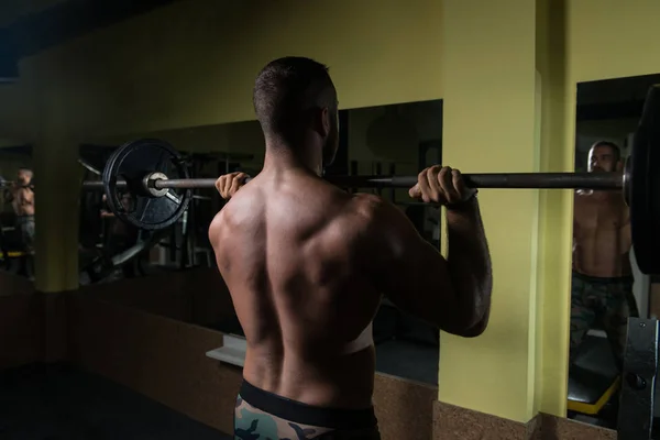 Мужчина в тренажерном зале упражнения плечо с штангой — стоковое фото