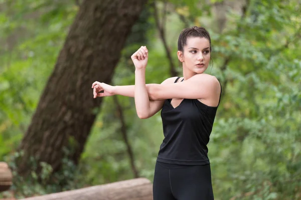 Sportswoman Stretching Arm in the Forest — Stock Photo, Image
