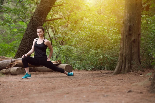 Mladá dívka Streching nohy před spuštěním venku — Stock fotografie