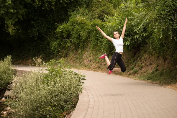Jeune femme sautant dans la forêt boisée — Photo
