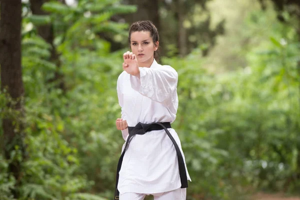 Mujer en blanco entrenamiento karate en parque — Foto de Stock