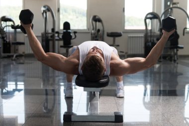 Genç adam için göğüs Dumbbells ile egzersiz yaparak