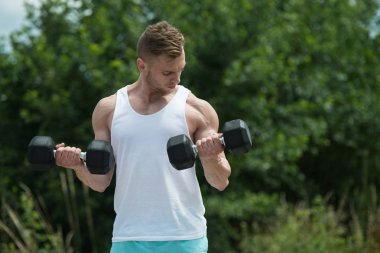 Pazı Dumbbells ile açık havada egzersiz vücut geliştirmeci