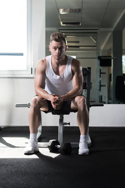 М'язистий чоловік після вправи відпочиває в тренажерному залі — стокове фото