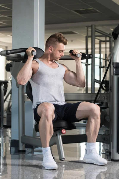 Bodybuilder Exercising Shoulders On Machine — Stock Photo, Image