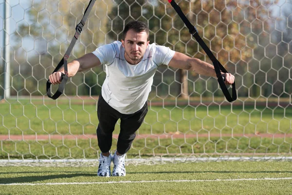 Genç adam trx askıları egzersiz Park yapmak