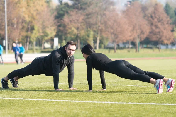 Para robi pompki trening w parku — Zdjęcie stockowe