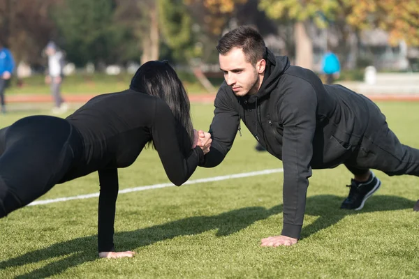 Casal de esportes fazendo flexões no parque — Fotografia de Stock