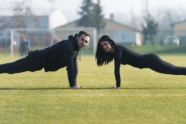 Parkta push-up egzersiz yaparak genç Çift — Stok fotoğraf