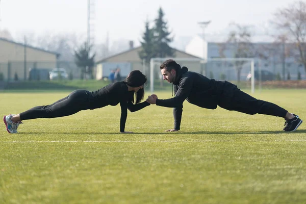 Casal atraente fazendo flexões no parque — Fotografia de Stock