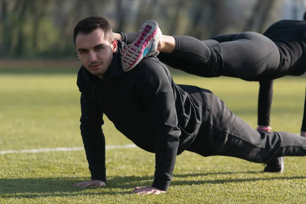 Parkta push-up egzersiz yaparak genç Çift — Stok fotoğraf